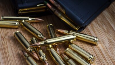 5.56x45mm (.223) AR-15 bullets laid out next to two loaded magazines full of ammunition