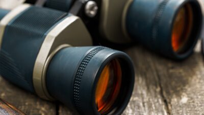 Hunting equipment binoculars on wooden background close up