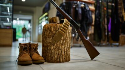 Rifle and hunting boots at the stump in gun store