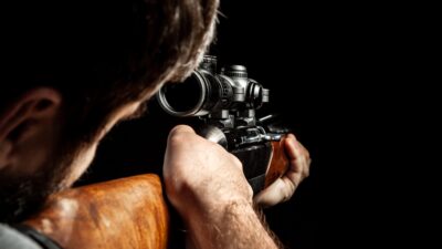Unrecognizable man aiming with a hunting rifle in dark